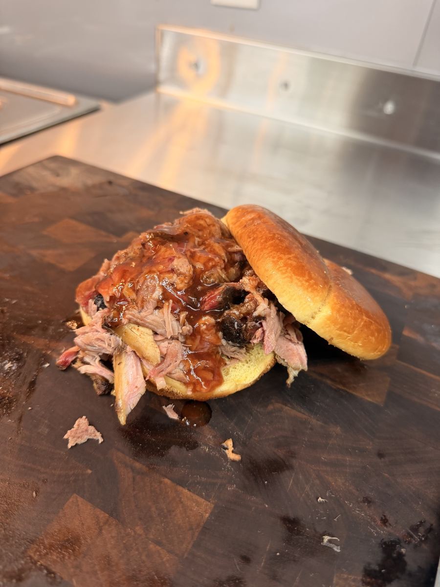 Open-faced pulled pork sandwich with BBQ sauce on a cutting board